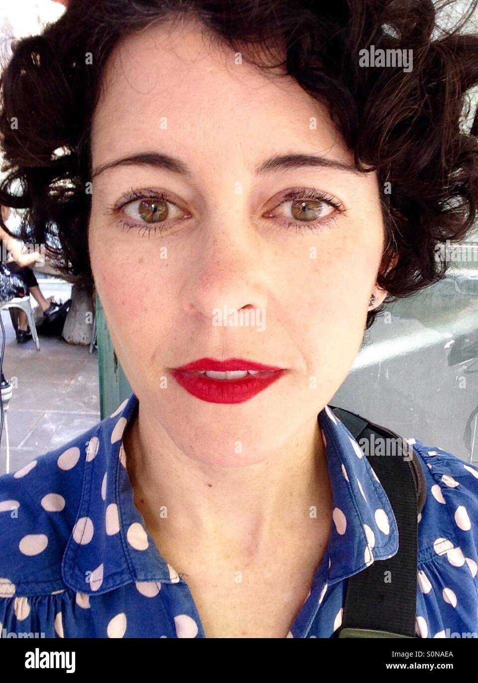 Brünette Frau mit rotem Lippenstift mit Polka Dot top Stockfoto