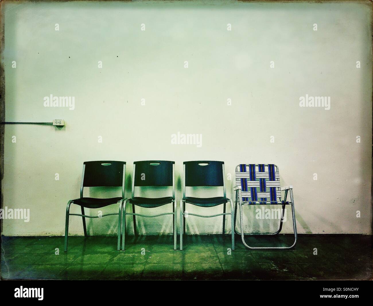 Vier Stühle gegen eine Wand mit einem Anderssein. Stockfoto