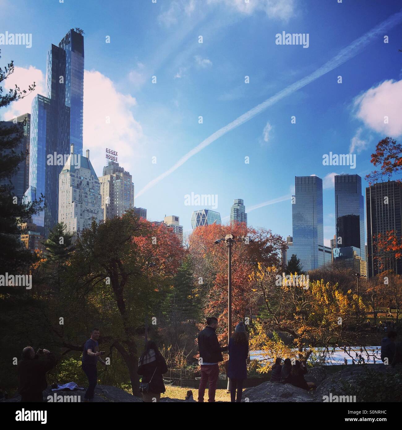 Herbstlaub im Central Park mit der Skyline von Manhattan und Wolkenkratzern im Hintergrund, farbenfrohe Herbstbäume in New York City, NYC Urban Park Land - Smartphone-aufgenommenes Stockfoto