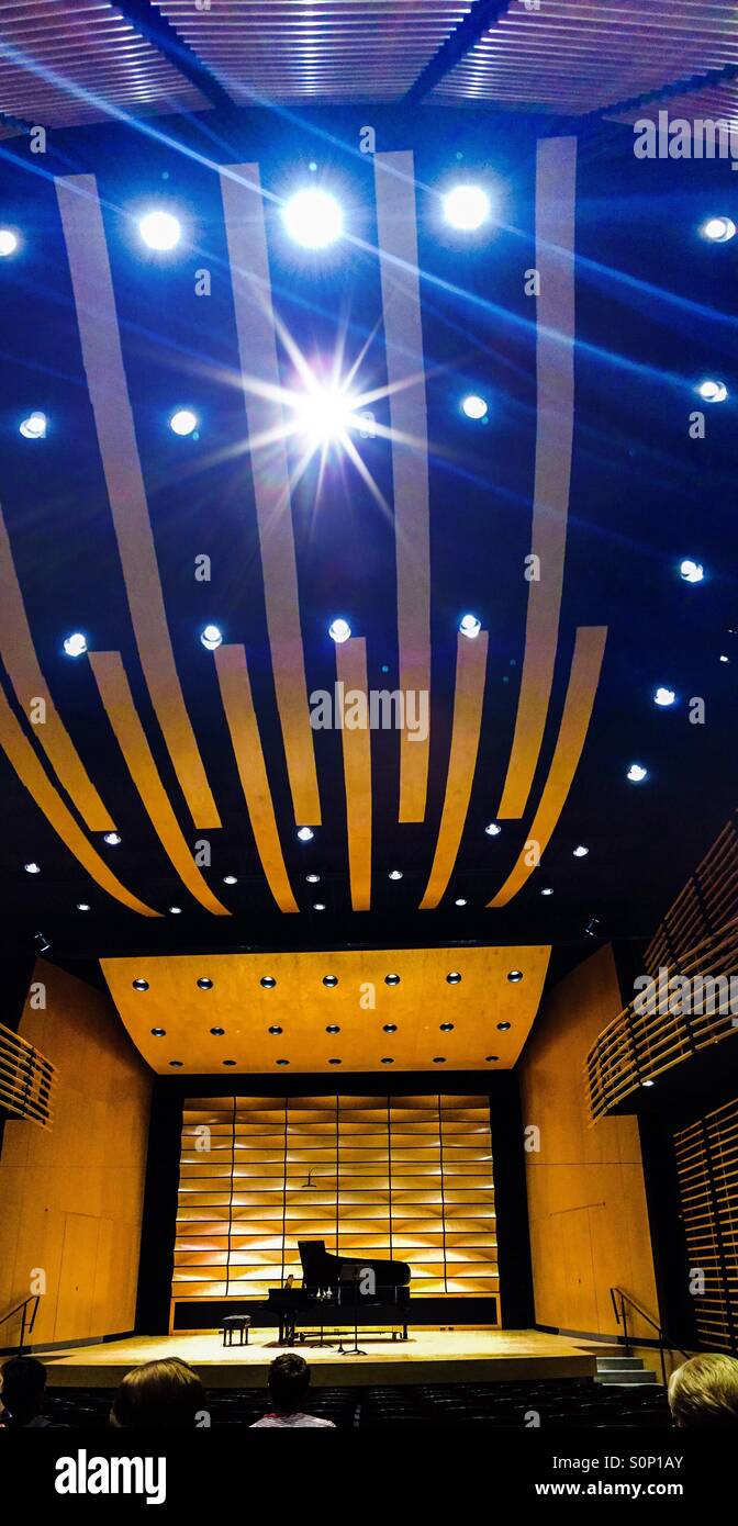 Das Innere eines kleinen Auditoriums mit einem sehr modernen Design. Die Holzbalken und -Platten tragen zu einer hervorragenden Akustik bei. Die Bühne ist für einen Klavierabend eingerichtet. - Smartphone-aufgenommenes Stockfoto