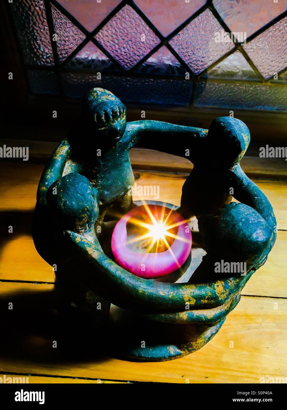 Lichtkreis. Ikonisches Bild von vier Menschen, Arme verbunden, um einen Lichtpunkt. Konzepte: Menschlichkeit, Menschheitsfamilie, Verbunden, Verbindung, Familie, Inspiration, tugendhafter Kreis, Ubuntu. - Smartphone-aufgenommenes Stockfoto
