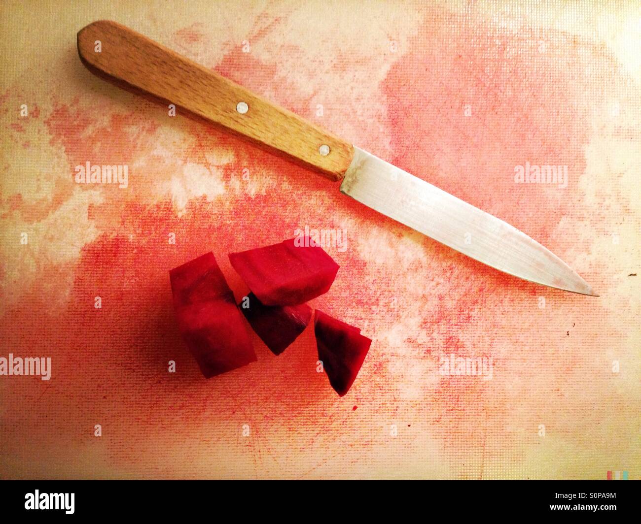 Rote Beete und ein Messer auf einem weißen Kunststoff Schneidebrett Stockfoto