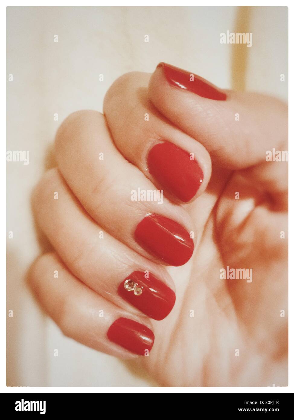 Rot lackierten Nägeln mit 2 Diamanten auf dem Ringfinger Nagel Stockfoto