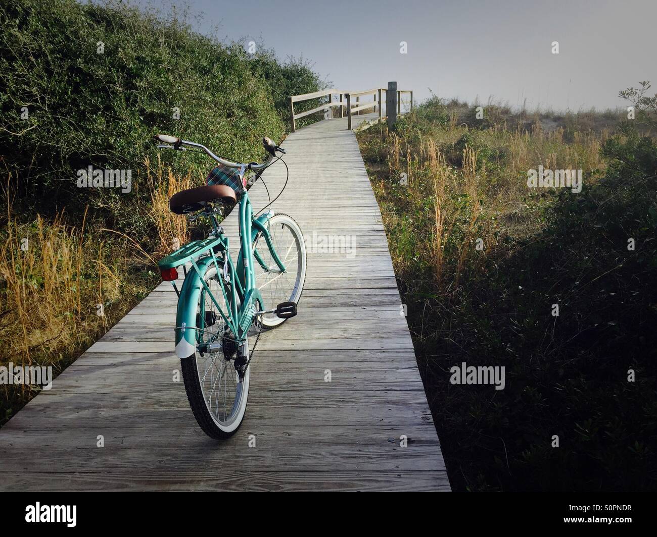 Ein Beach Cruiser-Fahrrad ist auf dem Weg zum Strand geparkt. Stockfoto