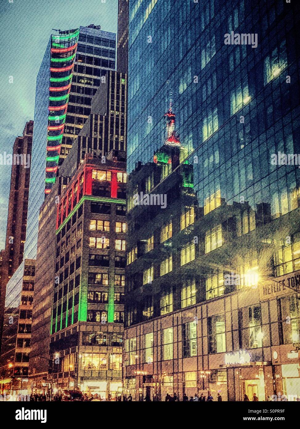 Sechste Avenue NYC ist ein Glühen mit roten und grünen Weihnachtslichter und Reflexionen auf dem Empire State Building. Stockfoto