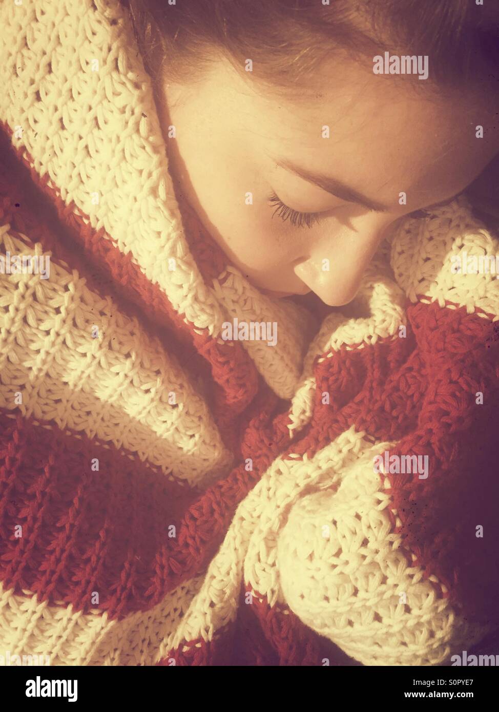 Teenager-Mädchen eingehüllt in eine gestreifte Decke schlafen Stockfoto