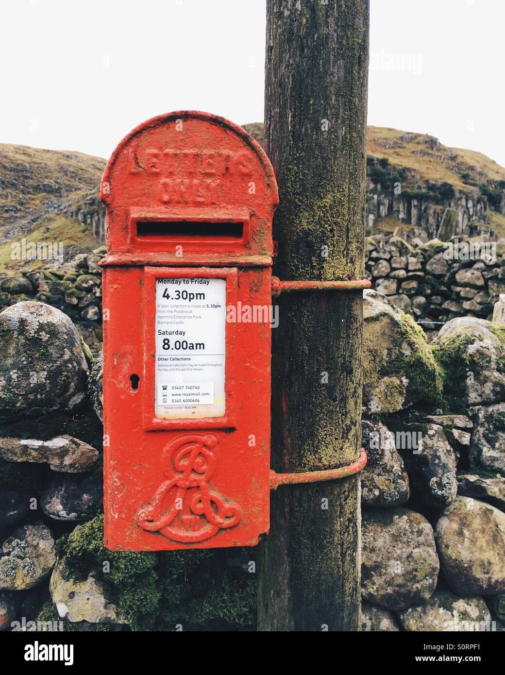 Eine kleine traditionelle rote Royal Mail Briefkasten im ländlichen Teesdale, UK. - Smartphone-aufgenommenes Stockfoto