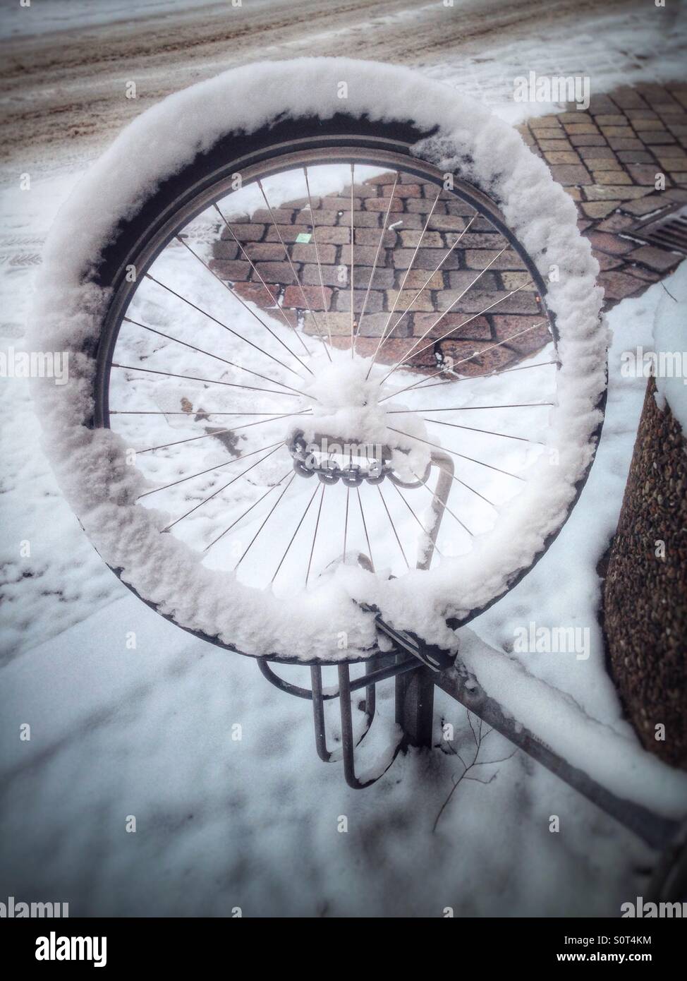 Ein Rad von einem gestohlenen Fahrrad links auf einem Fahrrad Parken Rack schneebedeckt, Berlin, Deutschland - Smartphone-aufgenommenes Stockfoto