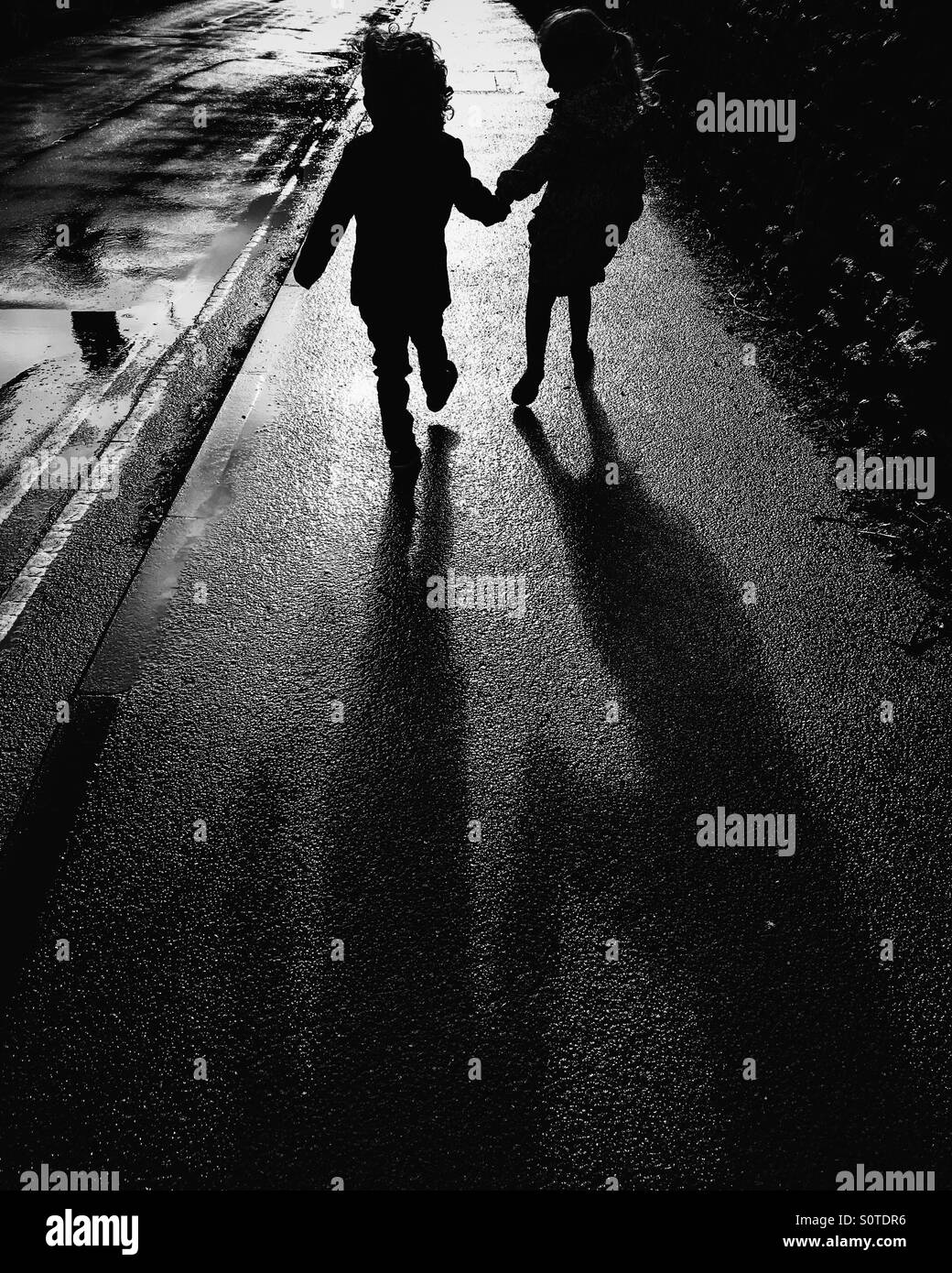 Silhouette von zwei Kindern, die Hände halten Stockfoto