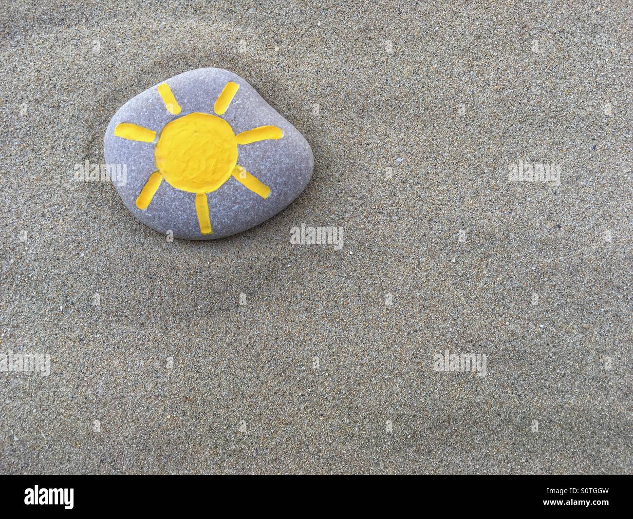 Steinsonne, konzeptionelles Steindesign über Strandsand Stockfoto