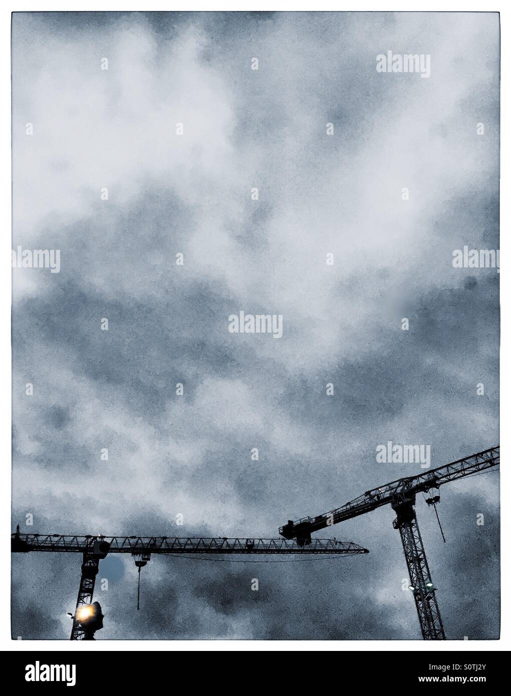 Hochbau-Krane gegen dramatische wolkenverhangenen Himmel. - Smartphone-aufgenommenes Stockfoto