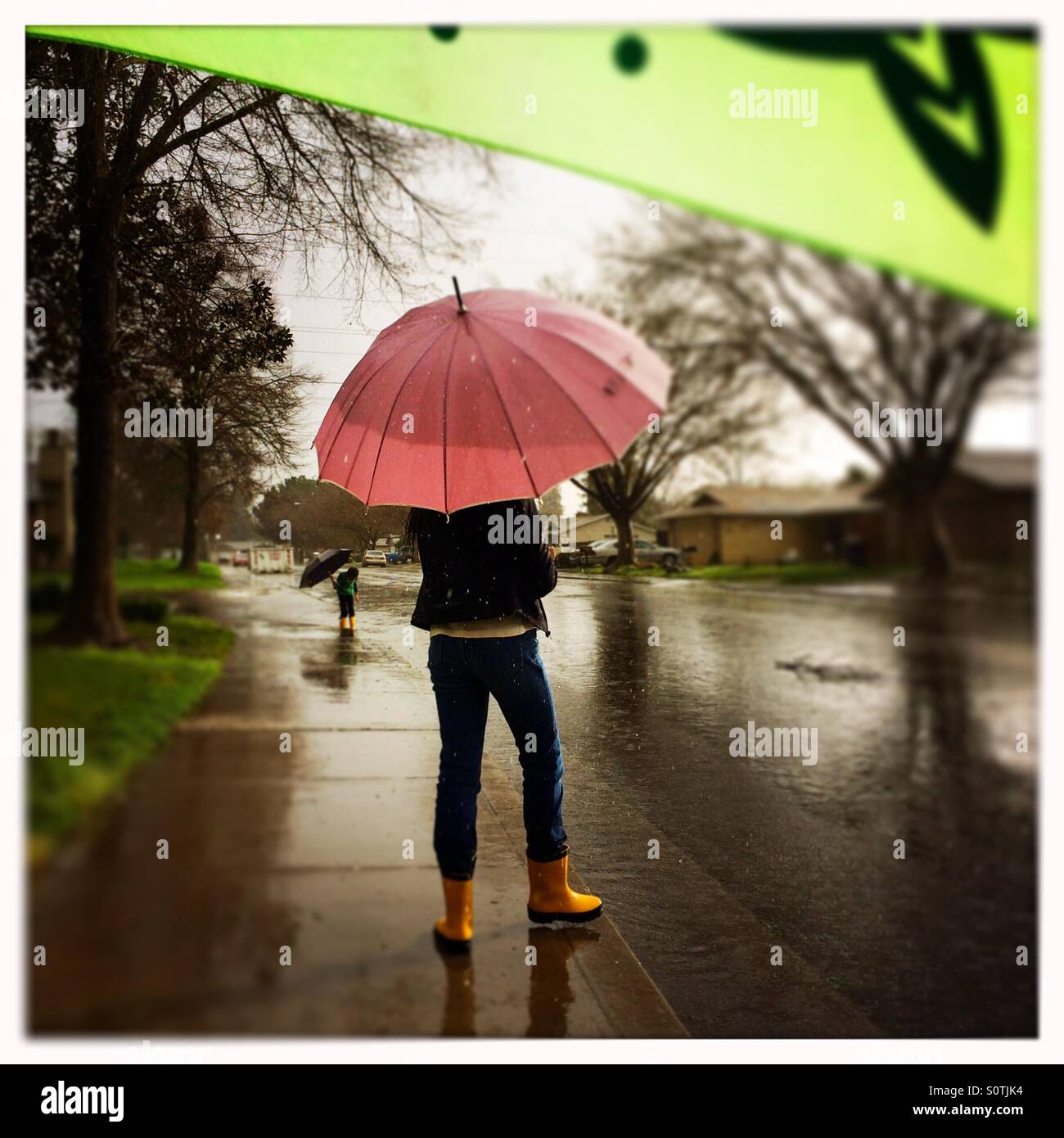 Ein 12 Jahre altes Mädchen und ihrem 7-jährigen Bruder draußen im Regen spielen. - Smartphone-aufgenommenes Stockfoto