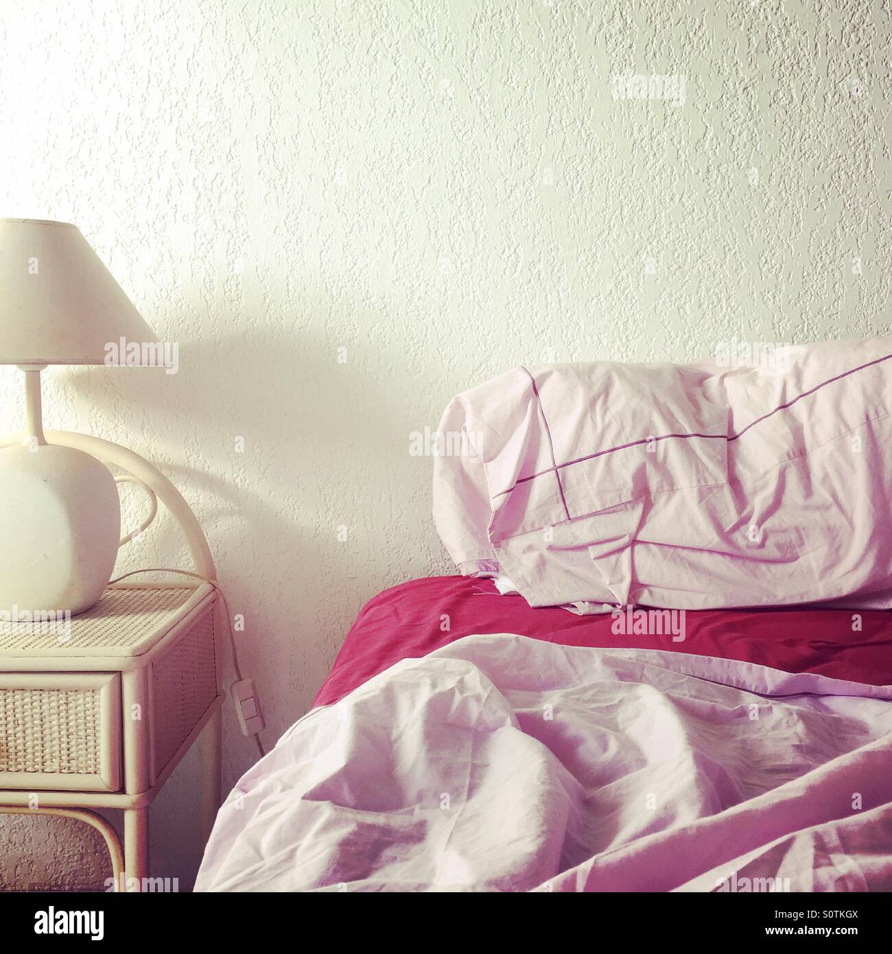 Rosa Laken auf dem Bett mit Nachttisch - Smartphone-aufgenommenes Stockfoto