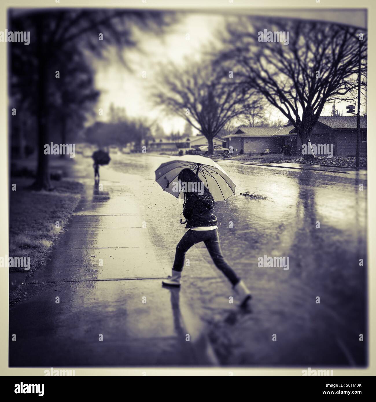 Ein 12 Jahre altes Mädchen und ihrem 7-jährigen Bruder draußen im Regen. - Smartphone-aufgenommenes Stockfoto