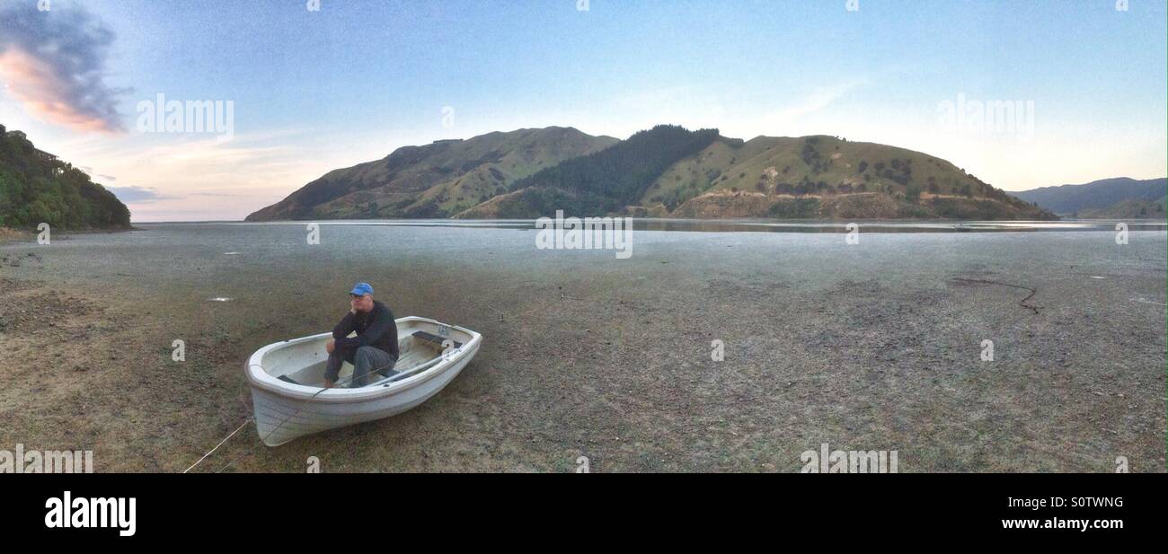 Mann in einem Boot bei Ebbe, Cable Bay, in der Nähe von Nelson, Südinsel, Neuseeland - Smartphone-aufgenommenes Stockfoto