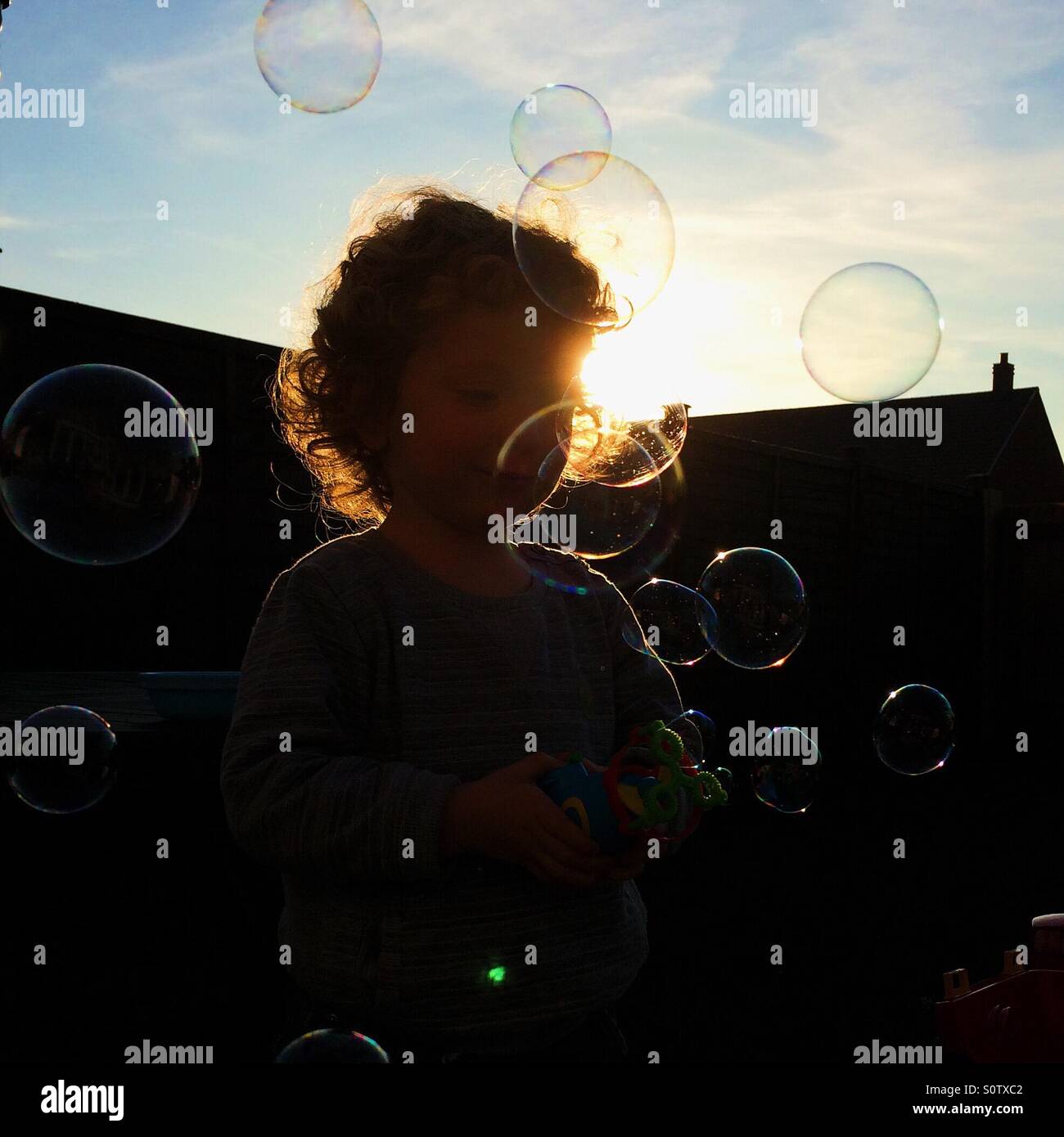 Silhouette Kind spielt mit Luftblasen im Garten Stockfoto