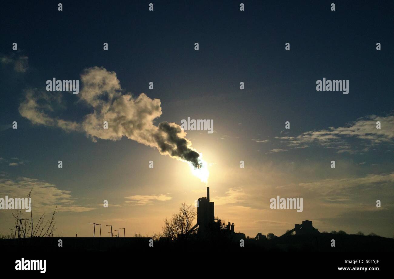 Sonne hinter Rauch aus Cemex Schornstein Stockfoto