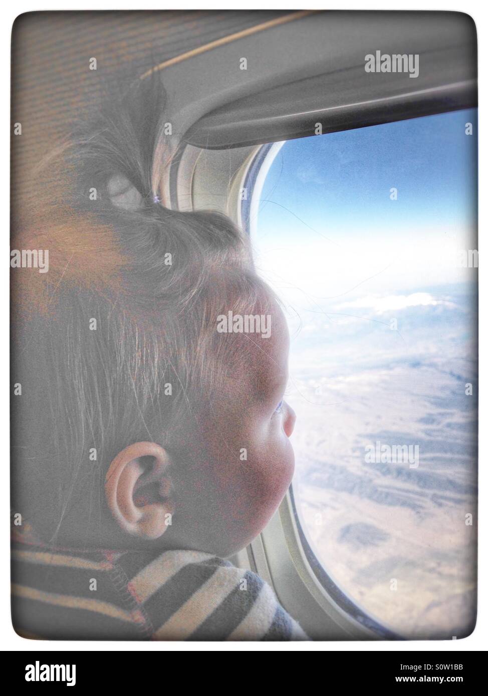 Baby schaut aus einem Flugzeugfenster Stockfoto