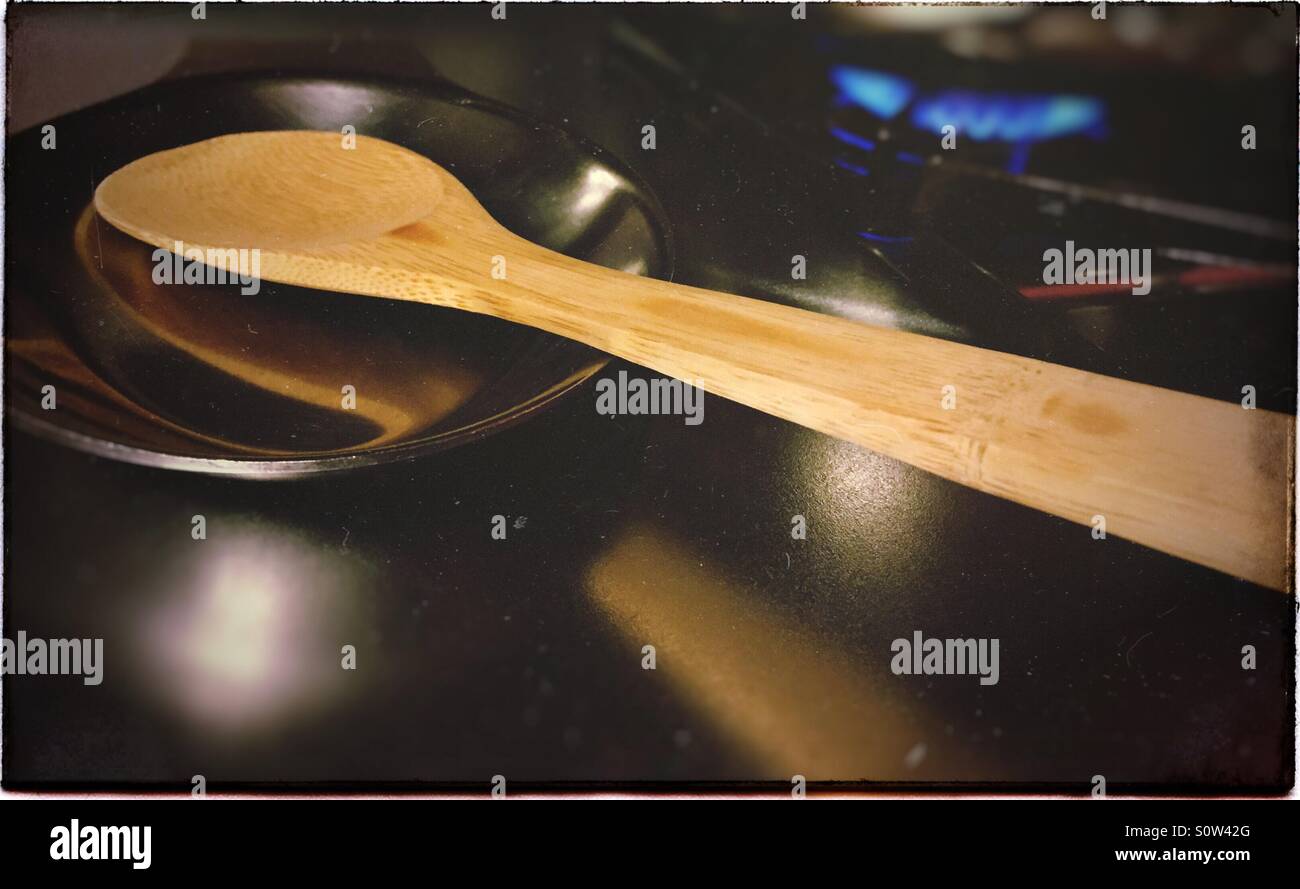 Holzlöffel auf einem Löffel Rest während Abendessen auf dem Herd kochen Stockfoto