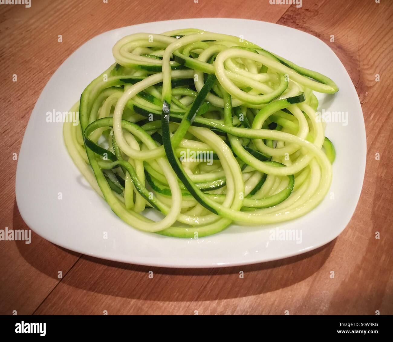 Zucchini, die wie Spaghetti auf ein Spiralizer auf einer Platte geschnitten worden ist. Stockfoto