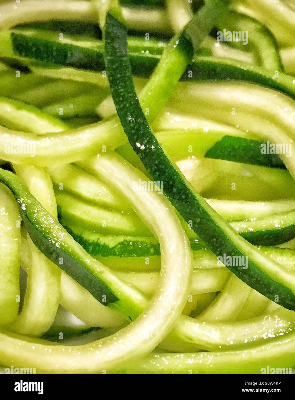 Nahaufnahme von frisch geschnittenen rohen Zucchini auf dem Teller. Das grüne Gemüse wurde in Spaghetti Form durch ein Spiralizer zerteilt. Stockfoto