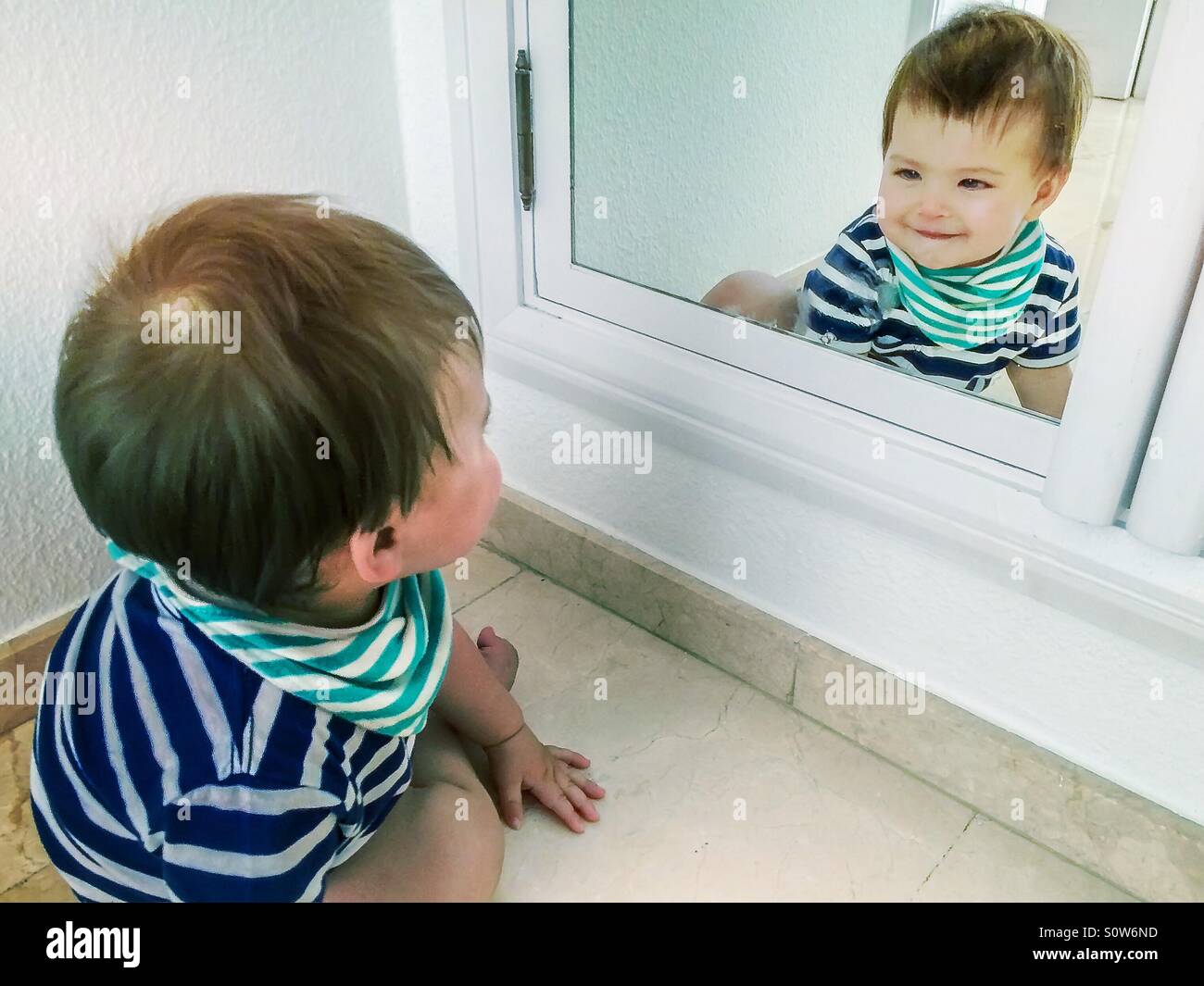 Süß lächelnden jungen selbst in einem Spiegel zu betrachten Stockfoto