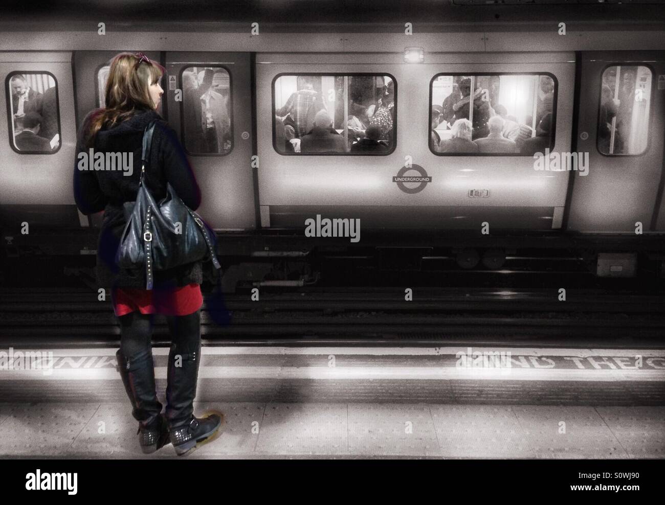 Frau wartet auf dem Zug am Bahnhof Barbican, London Stockfoto