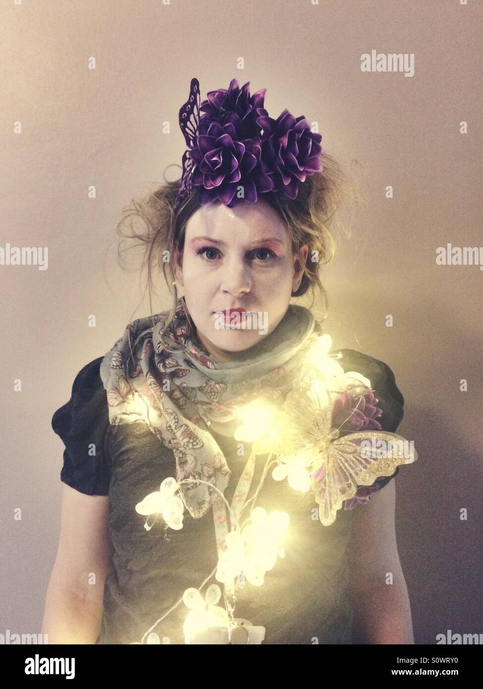 Mädchen verkleidet. Stark geschminkt und Kopf Kleid mit Schmetterlingen Lichter - Smartphone-aufgenommenes Stockfoto