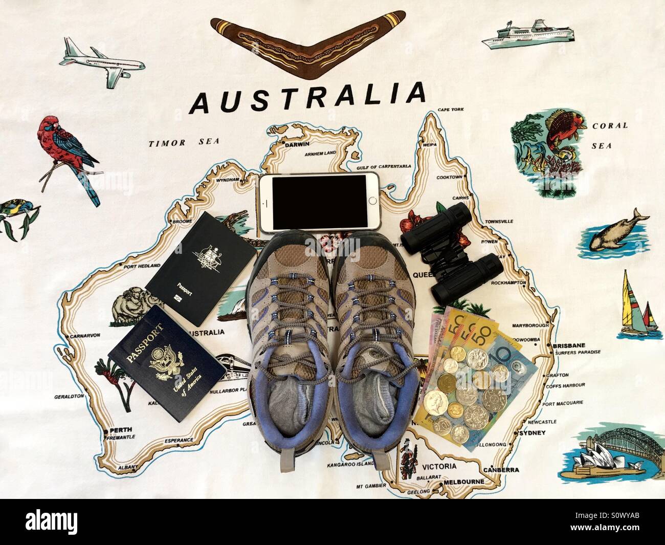 Ein paar Damen Wanderschuhe, Pässe, Fernglas, Smartphone und australische Währung innerhalb einer Karte von Australien - Smartphone-aufgenommenes Stockfoto