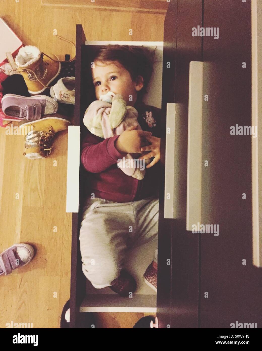 Niedliche kleine Mädchen liegen in der Schuh-Schrank Regal-Draufsicht Stockfoto
