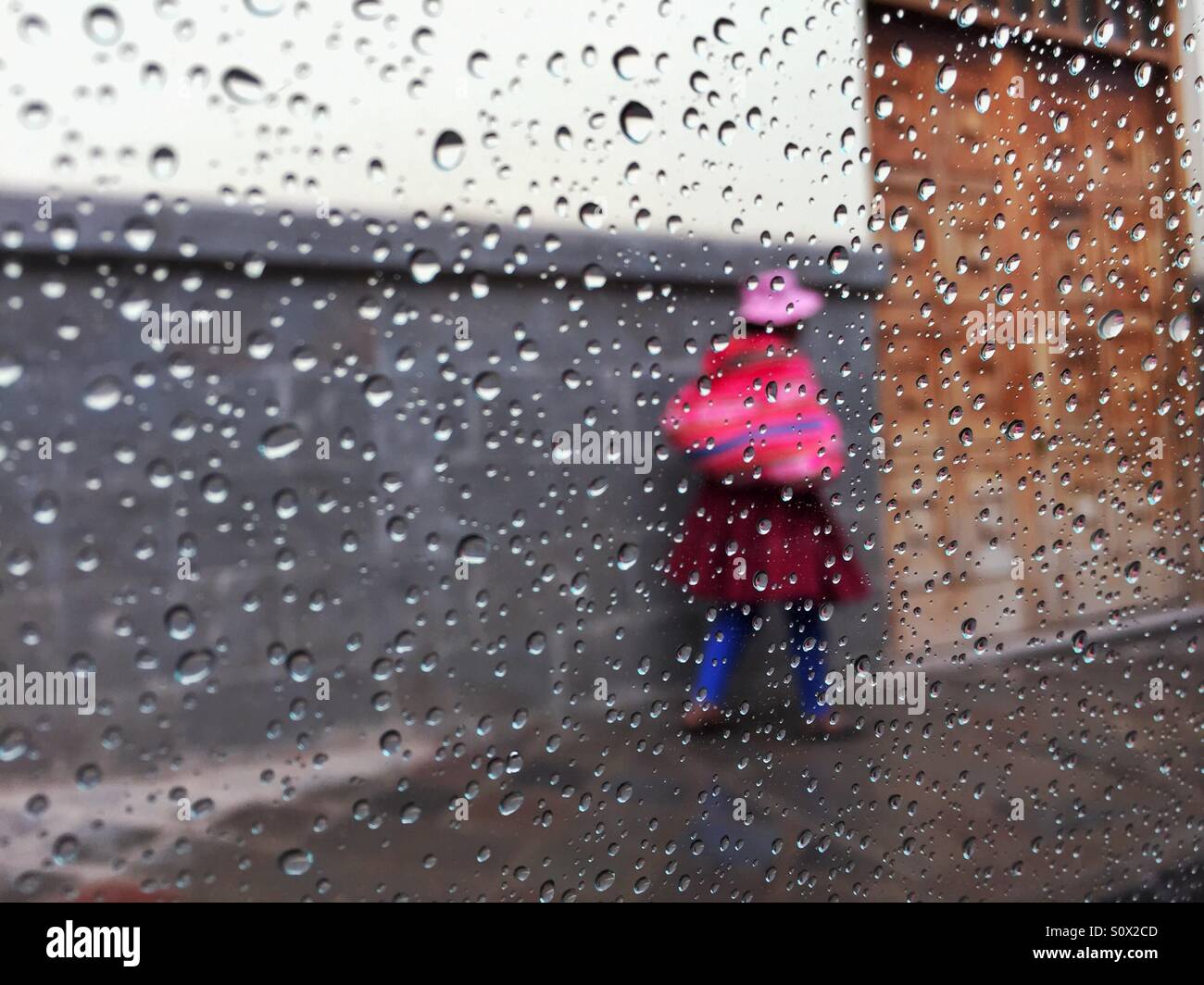 Frau ungewöhnlichen Outfit auf der Straße von Cusco, Peru, im Regen - Smartphone-aufgenommenes Stockfoto
