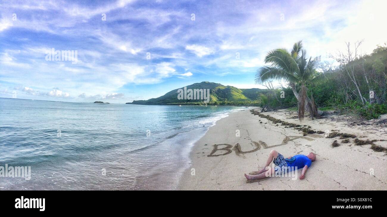 Bula geschrieben auf dem Sand mit Mann, Nacula Island, Yasawa Kette, Fidschi Stockfoto