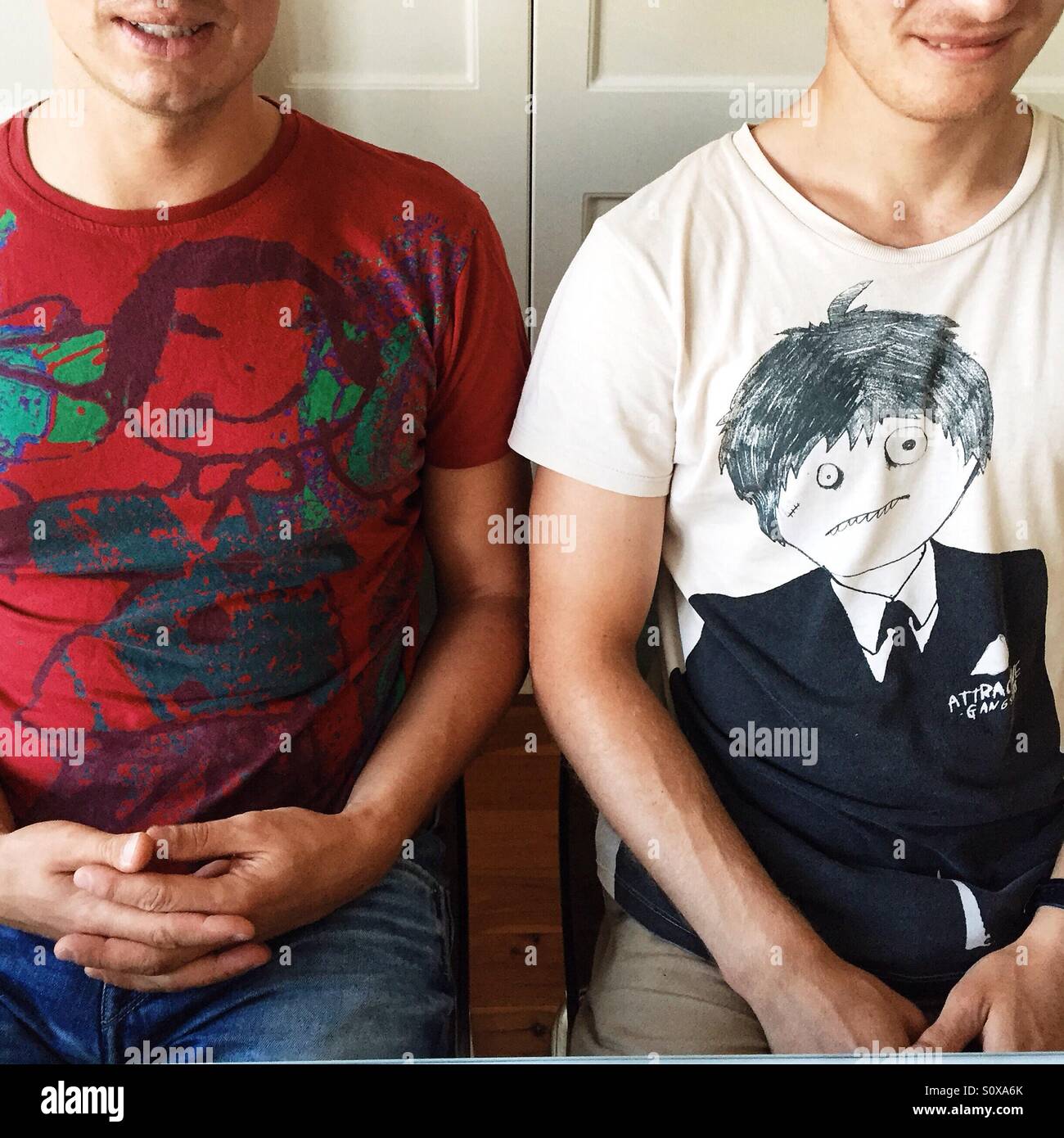 Zwei männliche Personen, die nebeneinander sitzen Stockfoto