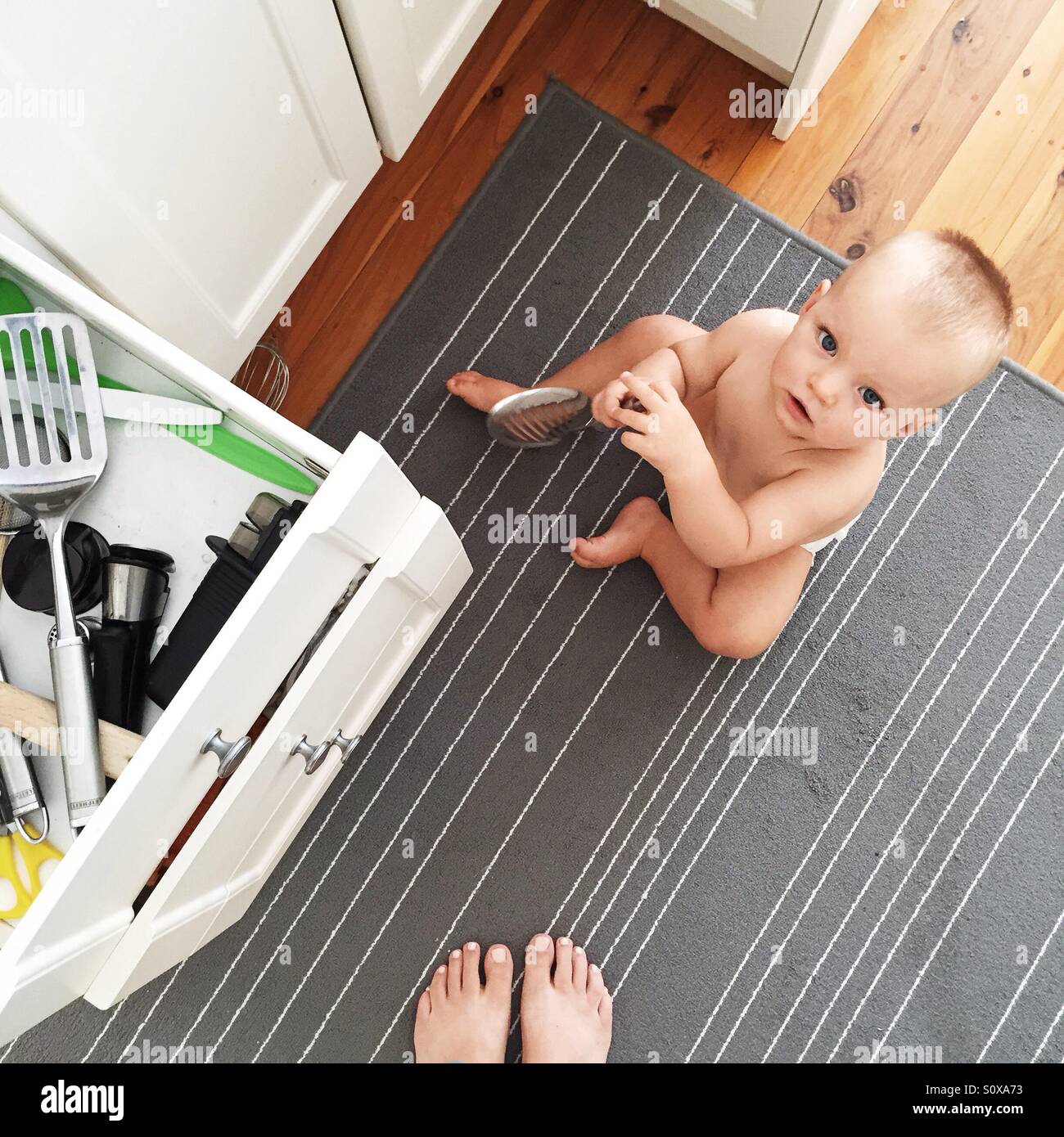 Kleinen Jungen sitzen auf dem Küchenboden Stockfoto