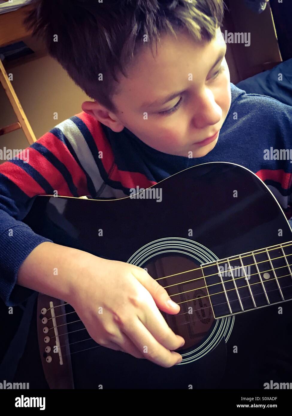 11 Jahre alter Junge seine Gitarre am Morgen Stockfoto