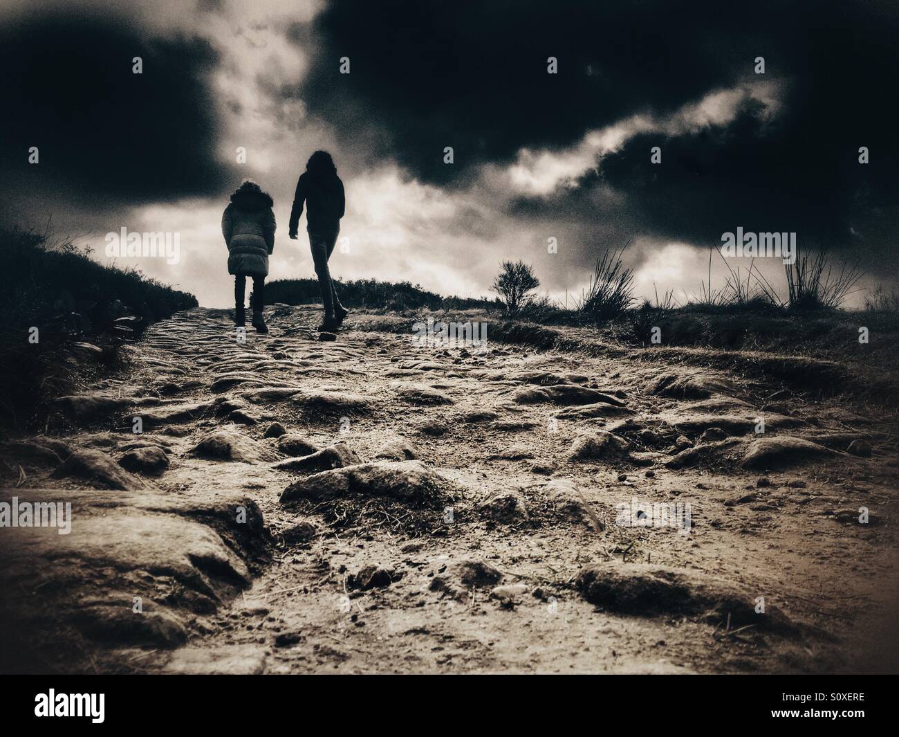 Zwei Mädchen zu Fuß bis steinigen Pfad an Rivington in Lancashire gegen eine repressive dunklen Himmel Stockfoto