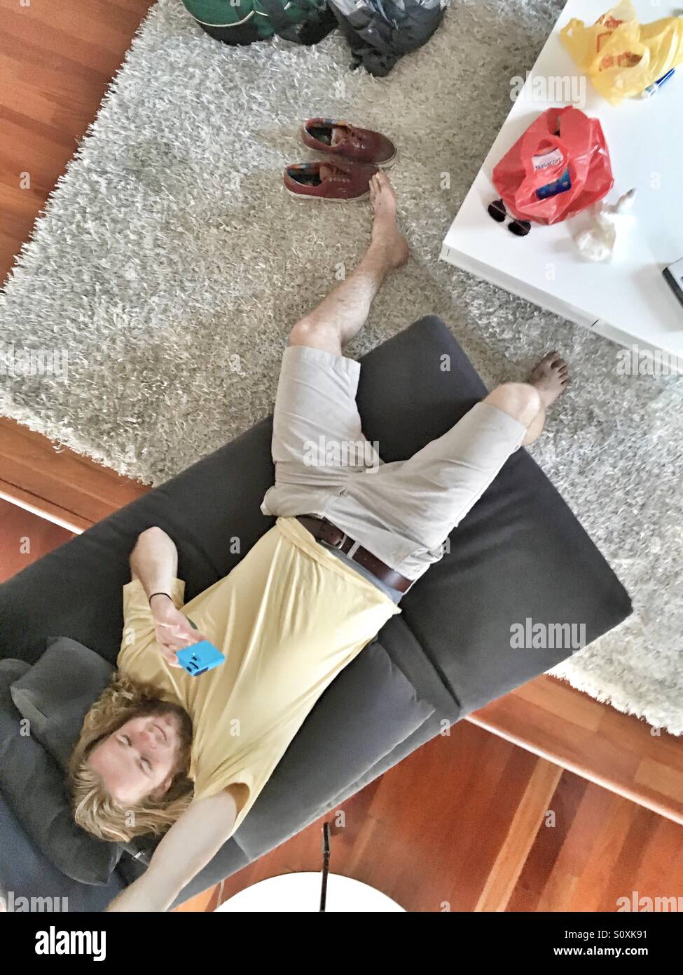 Junger Mann genießt seine Junggesellenbude mit smartphone Stockfoto