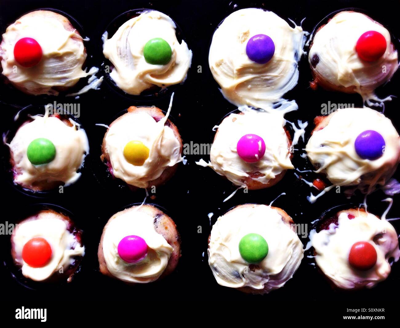 Muffins mit weißer Schokolade überzogen und verziert mit einem smartie Stockfoto
