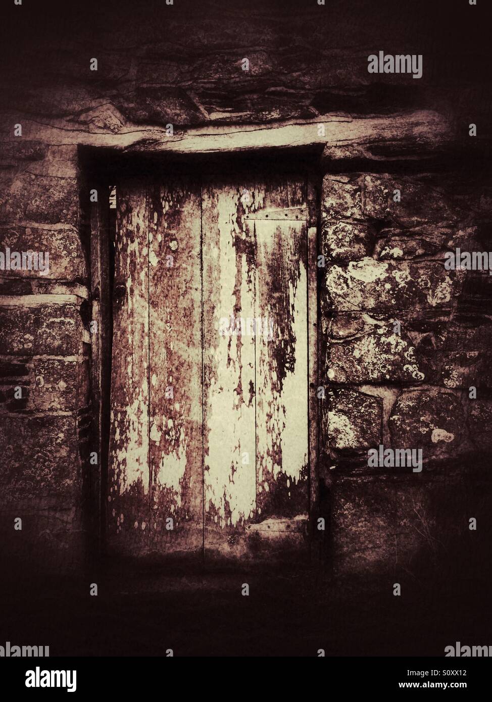 Holztür in einer alten Steinmauer - Smartphone-aufgenommenes Stockfoto