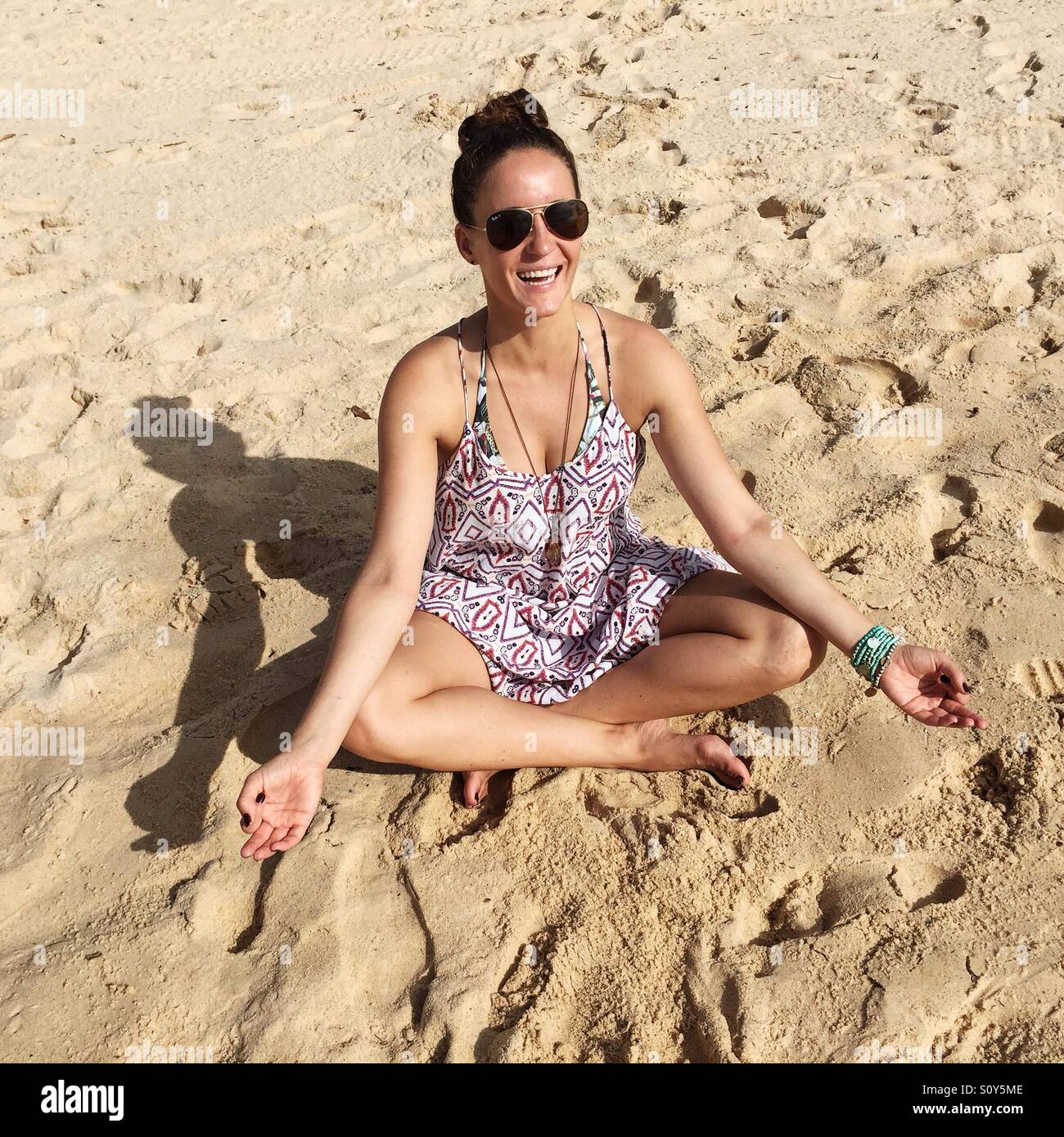 Glückliche Frau meditiert am Strand Stockfoto