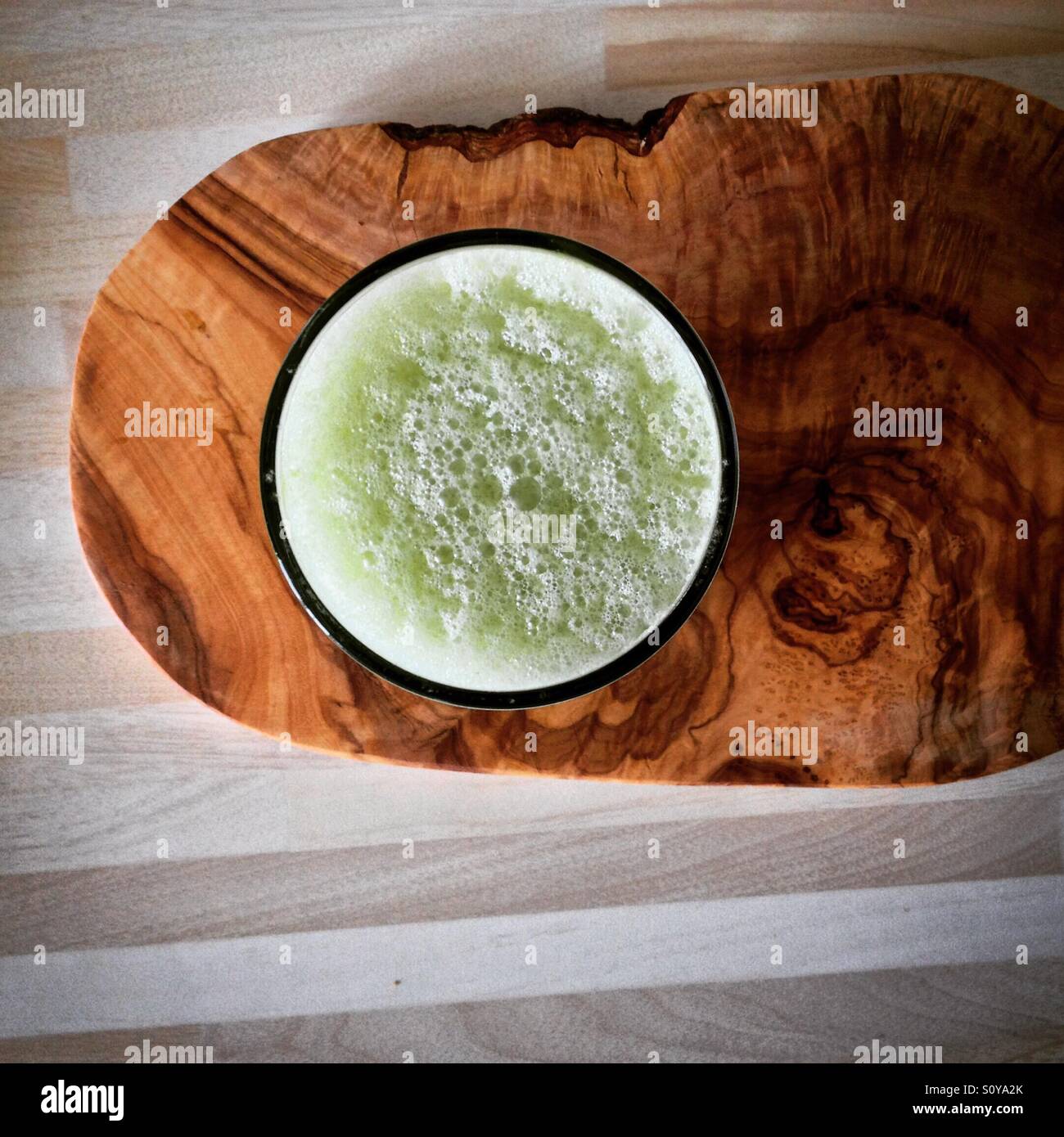 Blick von oben auf einen grünen Smoothie in einem Glas auf einer Küchenarbeitsplatte. Mobiltelefon-Foto mit einem Telefon oder Tablet Nachverarbeitung. - Smartphone-aufgenommenes Stockfoto