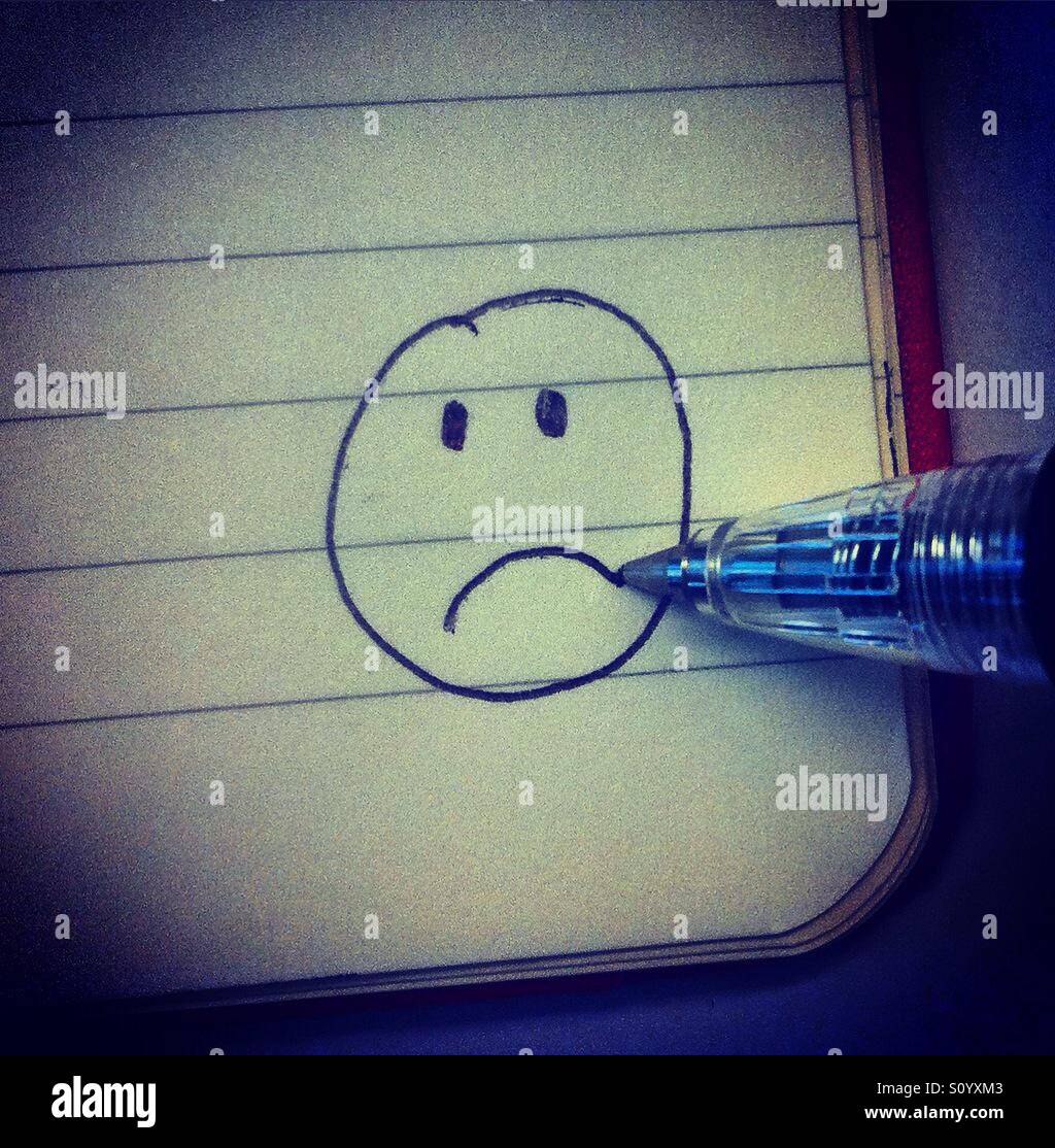 Einen traurigen Smiley zeichnen in der Ecke ein Booknote mit einem Bleistift Stockfoto