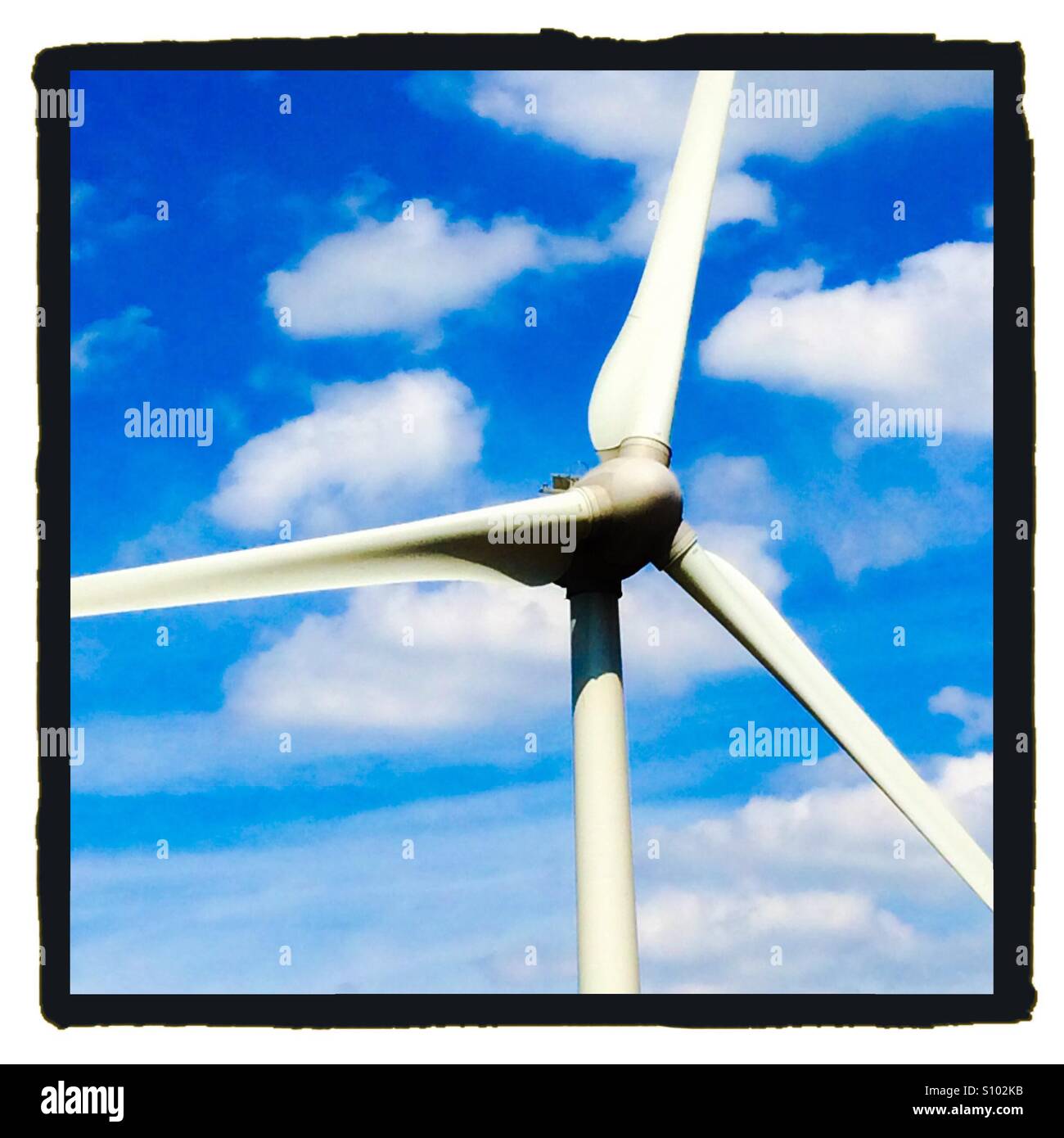 Rotorblätter einer Windkraftanlage mit blauem Himmel und weißen Wolken hinter - Smartphone-aufgenommenes Stockfoto