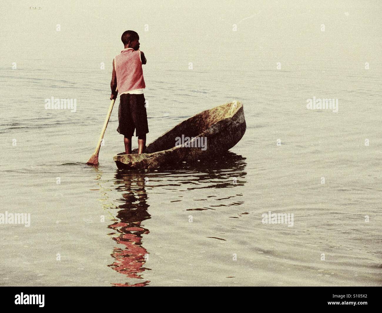 Junge im rosa Hemd Rudern im Boot aus Baumstamm, Northern Province, Sambia Stockfoto