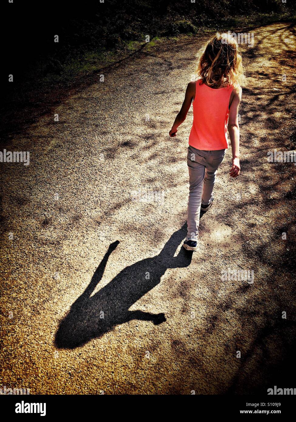 Junges Mädchen zu Fuß Gießen Schatten Stockfoto