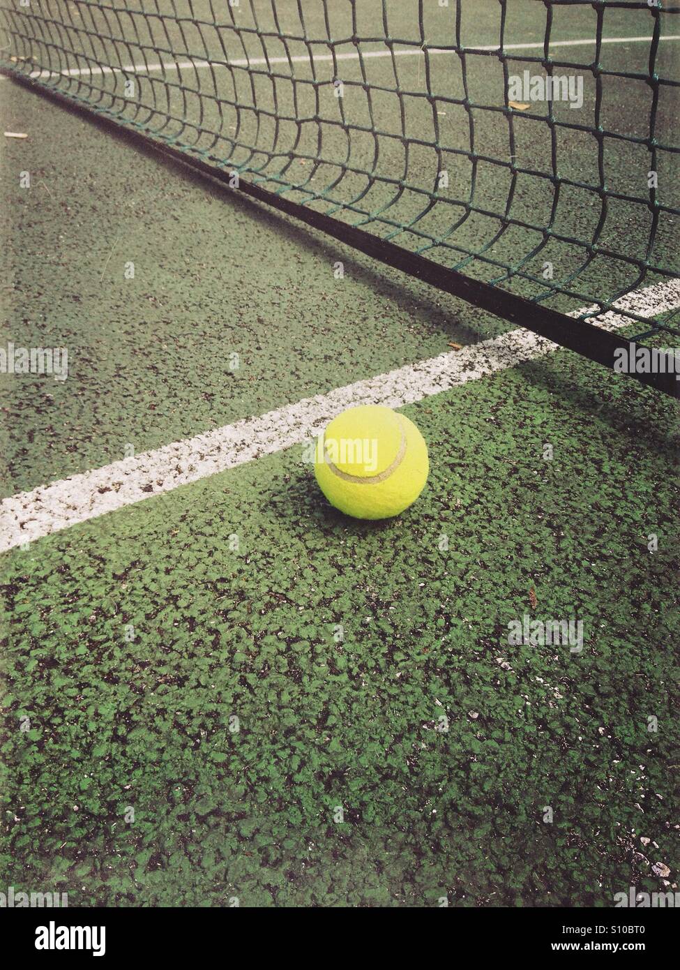 Tennisball in der Nähe eines Netzes und einer weißen Linie auf einem Tennisplatz - Smartphone-aufgenommenes Stockfoto