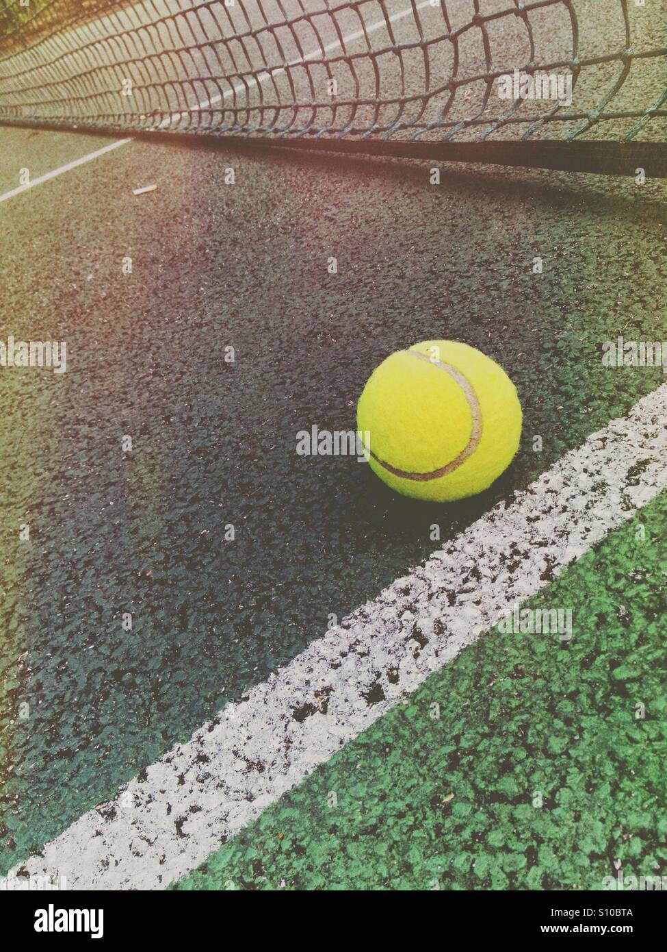 Tennisball in der Nähe eines Netzes auf einem Tennisplatz - Smartphone-aufgenommenes Stockfoto