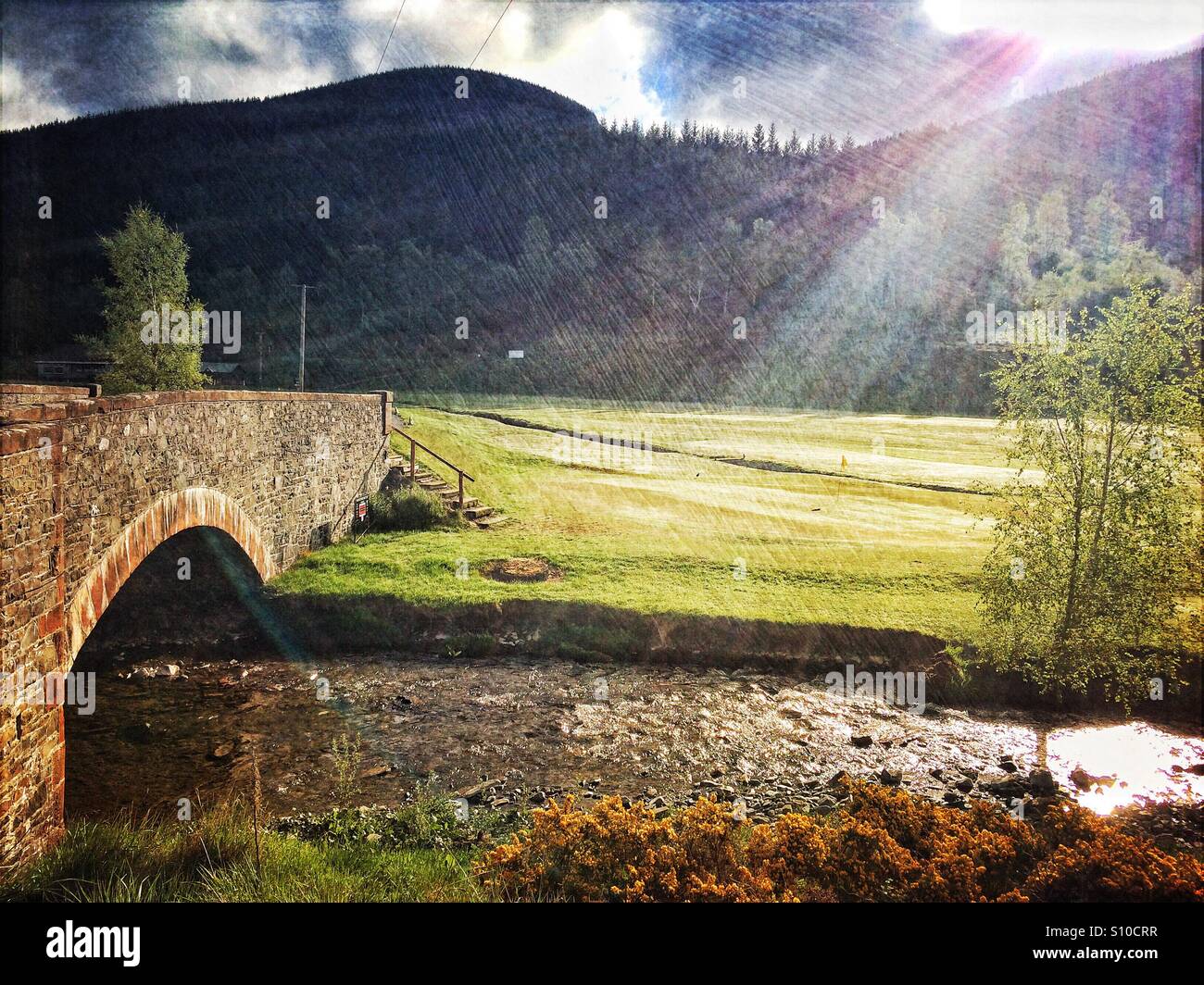 Morgensonne blickt über die Hügel mit Blick auf Golfplatz Innerleithen und Leithen Wasser, das unter einer Steinbogenbrücke Süden fließt. Stockfoto