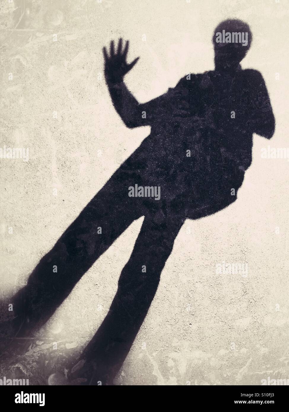 Shadow Casting eines Mannes winken, projiziert auf dem Bürgersteig. Stockfoto
