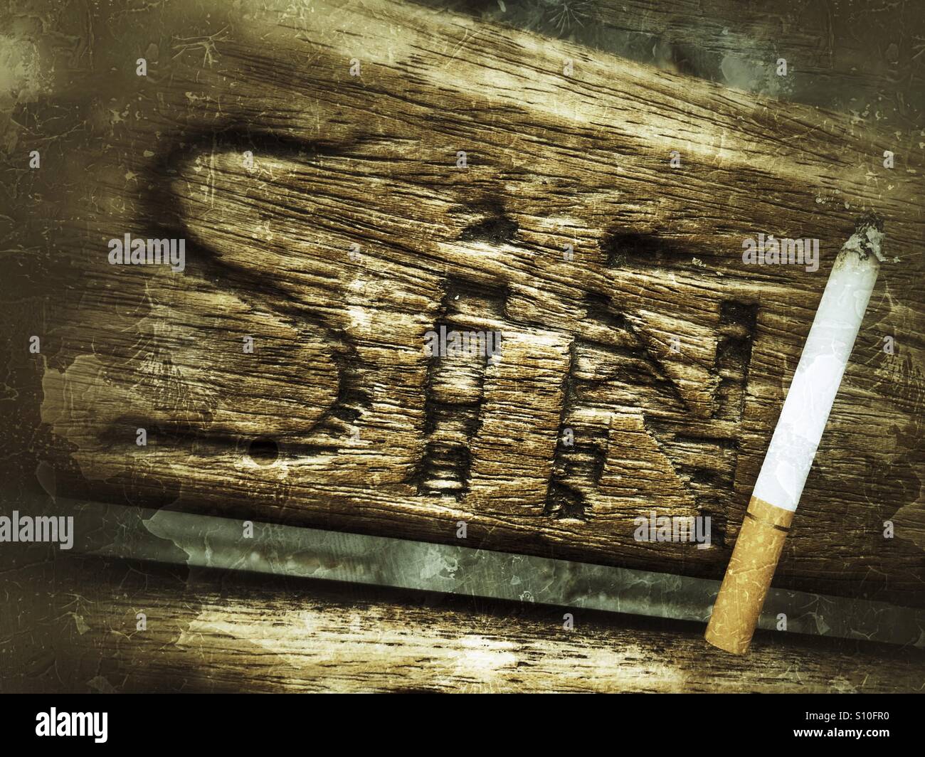 Das Wort "Sünde" geschnitzt auf einer Holzbank und einer Zigarette in der Nähe Stockfoto